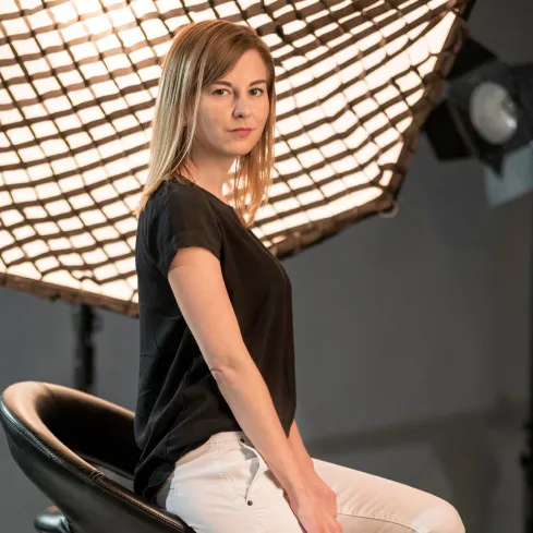 Žena sedí bokem na židli ve studiu